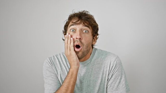 Amazed young man in t-shirt, with shocked face expression, showing fear and amazement; excited and surprised isolated against white background