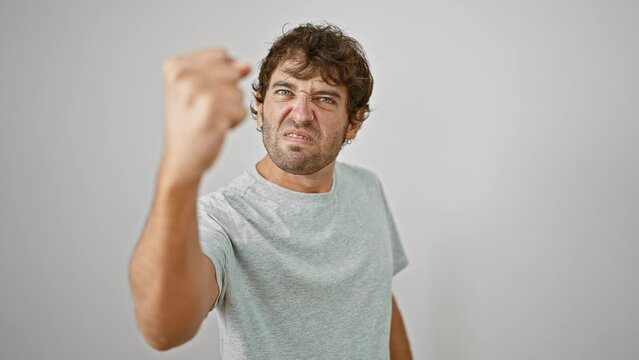Furious young man, fists clenched in rage, venting anger in a mad scream. frustrated adult in t-shirt on isolated white background. aggressive expression of a serious, unhappy person.