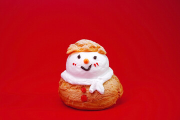 Snowman Choux Cream isolated on red background. Choux pastry snowman, Ideas for Christmas food, DIY, Do It Yourself. Greeting card for Christmas and New year, copy space for Text