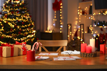 Santa's Claus workplace. Gift boxes, letters and candy canes on table in room with Christmas decor
