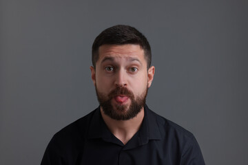 Fototapeta premium Personality concept. Handsome man showing tongue on grey background
