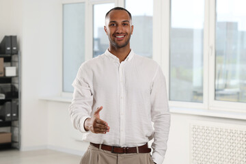 Happy man welcoming and offering handshake in office