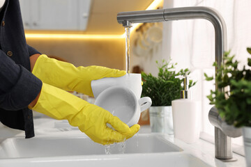 Woman washing cup at sink in kitchen, closeup