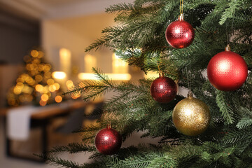 Christmas tree decorated with red and golden festive balls against blurred background, bokeh effect. Space for text
