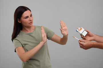 Stop smoking concept. Woman refusing cigarettes on grey background