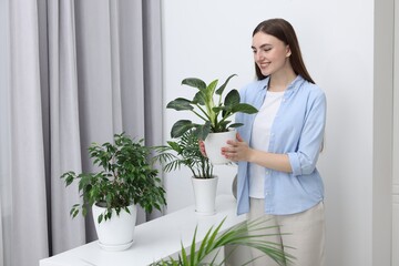 Beautiful young woman with green houseplants at home
