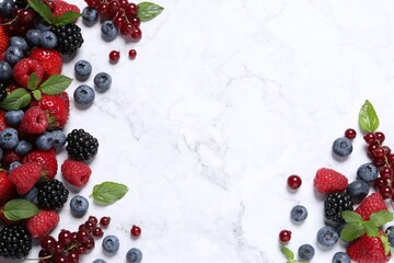Many different fresh ripe berries on white marble table, flat lay. Space for text