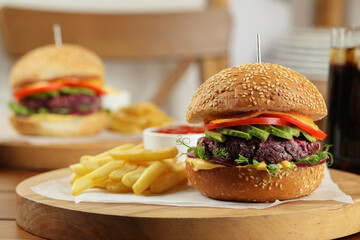 Tasty vegetarian burger served with french fries on wooden table, closeup. Space for text