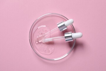Pipettes and petri dish with serum sample on pink background, top view