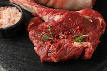 Raw ribeye steak and spices on grey table, closeup