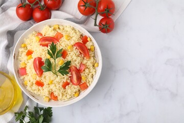 Tasty couscous with parsley, corn and tomatoes served on white marble table, flat lay. Space for...