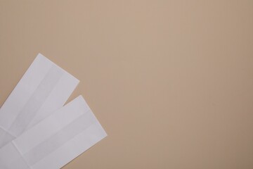 Two white paper bags on beige background, top view. Space for text