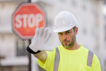 Builder with stop road sign. Builder with stop gesture, no hand, dangerous on building concept. Man in worker uniform and hardhat with open hand doing stop sign.