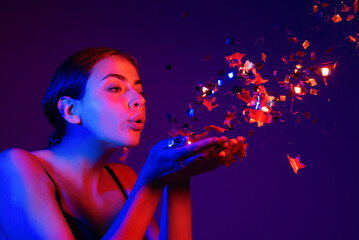 Sensual girl blowing confetti. Portrait of beautiful young lady on birthday valentines day. Sexy...