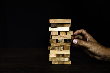 Hand pull wooden block tower stack in pyramid stair step with caution to prevent collapse or crash concepts of financial risk management and strategic planning and business challenge plan.