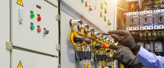 Electricity and electrical maintenance service. Engineer hand checking electric current voltage at circuit breaker terminal and cable wiring in main power distribution board AHU starter control panel.