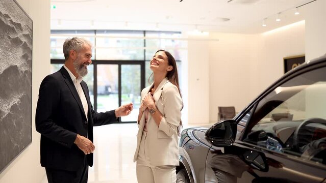 Charming salesman selling the car to a beautiful customer