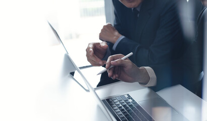 Two businessmen having a discussion, working on laptop computer, using digital tablet and mobile phone during meeting at office. Business planning and solution, working together concept