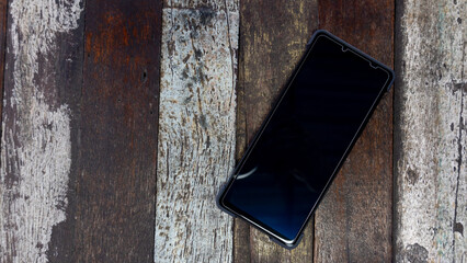 Above view of smart phone with a shiny black frame. Placed on a wooden floor that is a variety of beautiful.