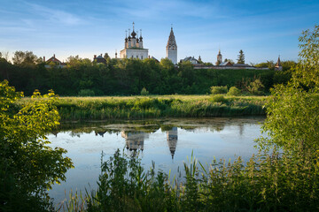 Fototapeta na wymiar View of the Church of the Ascension of the Lord with a bell tower in the Alexander Monastery on the banks of the Kamenka River on a sunny summer day, Suzdal, Vladimir region, Russia