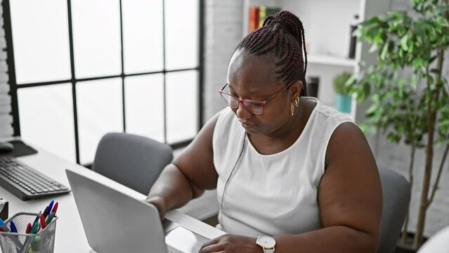 Focused african american woman worker excelling in business. working diligently at her laptop, this boss lady embodies success and professionalism in her office.