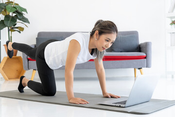 Online Yoga Tutorial: Young Woman Practices Yoga at Home