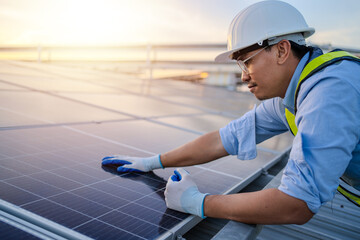 Asian electrical engineer in hardhat and uniform installs solar panels in electric power station....