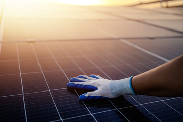 Close-up of a young engineer's hand inspecting the cleanliness of a solar panel. Concept: Renewable...