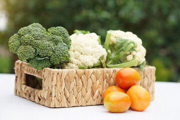 Basket of organic vegetables from garden. Broccoli, cauliflower and tomatoes. Outdoor background. Concept, food ingredient. Healthy eating, source of vitamins, fiber and nutritions. Fresh from garden.