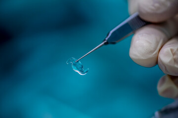 Close-up of synthetic lens used during lens replacement cataract removal procedure. The folded lens...