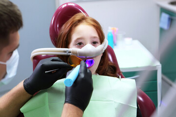 A little girl is being treated for her teeth with a sedative. Treatment of baby teeth. Anesthesia with nitrous oxide.