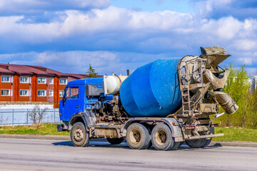 A large automobile concrete mixer drives along the road to a construction site. Blue concrete truck...