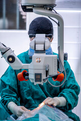 Surgeon removing cataract and replacing lens in a delicate procedure, using a microscope and synthetic lens.