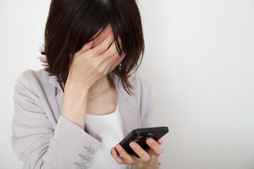スマホを見て落ち込む女性