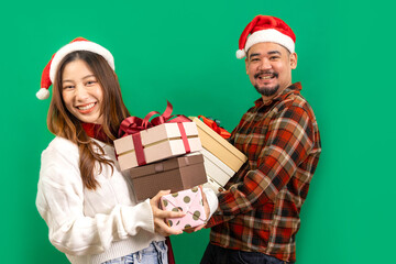 Asian people couple hold boutique bags pile stack newyear giftbox isolated on green color background. Happy New Year celebration Christmas holiday.