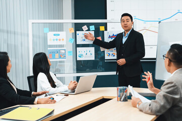 Successful businessmen present financial projects on glass whiteboard confidently. Executive...