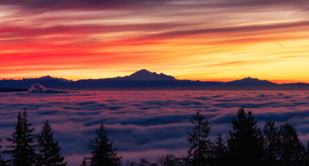 Fototapeta na wymiar Colorful Sunrise with Vancouver covered in Fog and Mt Baker in Background.