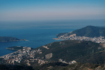 View from the top of the mountain to the settlements at the foot of the mountains on the seashore against the blue sky