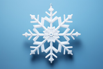 Close up photograph of a snowflake Christmas ornament isolated on a blue background