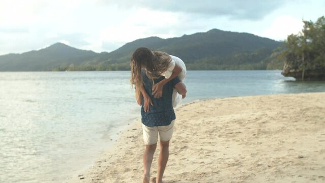 Happy couple, woman and laugh for carry on beach for bonding, playful and memory on vacation. Man, wife and smile for fun activity with love, care and support in relationship with romance for trip