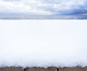 Wooden base covered with snow. Winter seascape. The backdrop. Drifts of snow. On the street. Winter. The sea shore covered with snow. Horizon. Winter nature. Natural background. North. Copy space