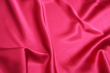 Bright red satin or silk fabric with soft folds. Background.