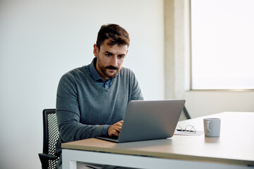 Male entrepreneur working on laptop in office.