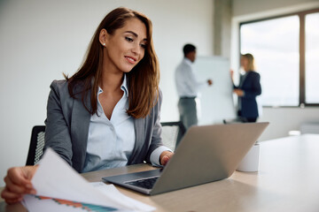 Obraz na płótnie Canvas Happy businesswoman working on laptop in office.
