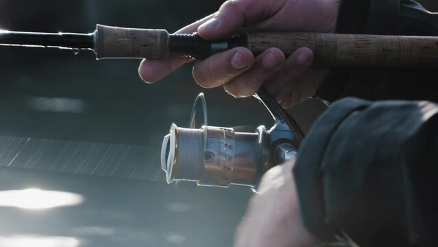 The angler reels in. He's fishing with a spinning reel.