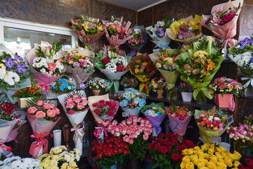 photo of a flower shop display with a variety of colorful bouquets wrapped in paper and arranged on...