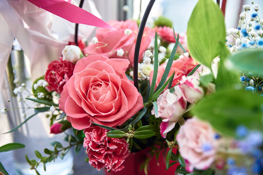close up photo of a beautiful bouquet of flowers. The bouquet is made up of pink roses, white and pink carnations, and green leaves.