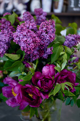 bouquet of fresh lilacs and peonies in a glass jar. The flowers, in hues of purple and pink, are beautifully natural background