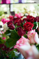 vibrant display of various flowers in a florist’s shop window. The arrangement includes red and pink roses, white flowers, and green leaves