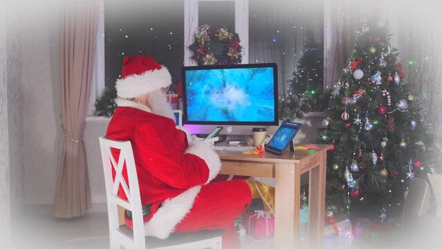 Santa Claus is sitting at his desk and looking at something on his phone while checking messages before celebrating Christmas.